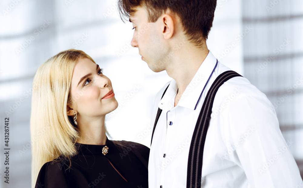 Young couple of businessman and woman are standing in a modern office. Portrait of successful business people Young couple of businessman and woman are standing in a modern office. Portrait of successful business people