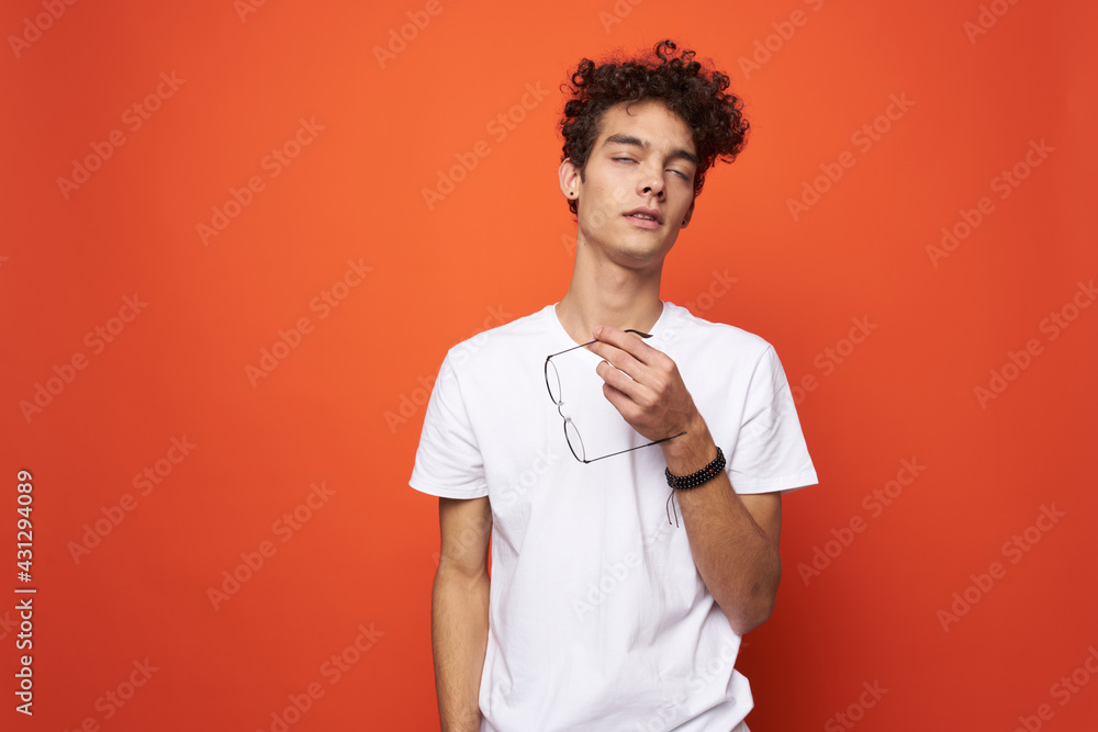 man with curly hair and glasses white t-shirt licks orange background man with curly hair and glasses white t-shirt licks orange background