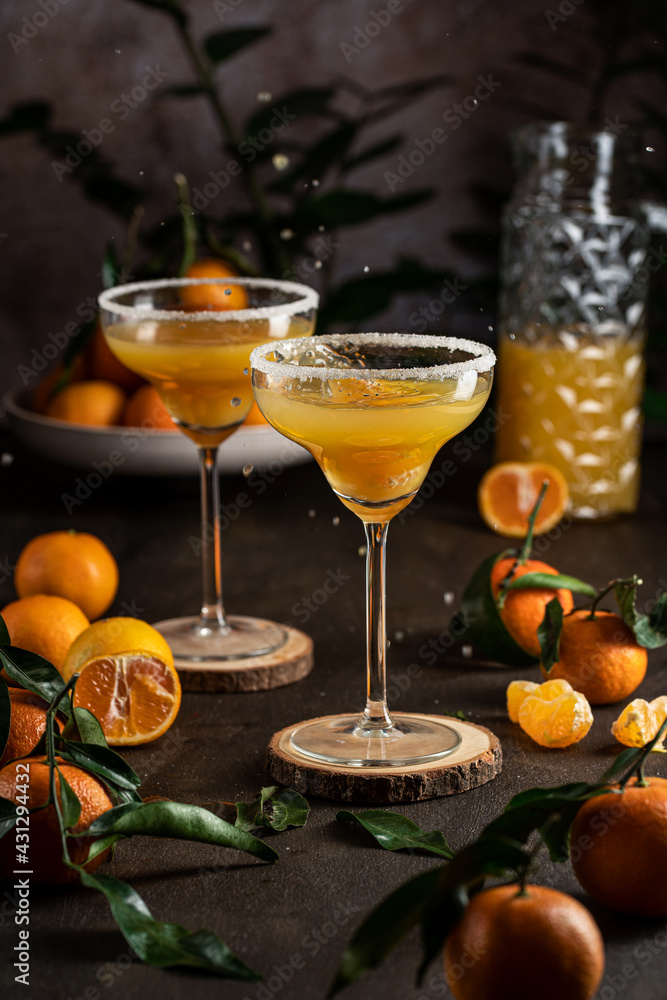 Orange juice in margarita glass surrounded by tangerines and water drops