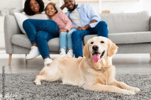 Happy black family sitting in living room with pet