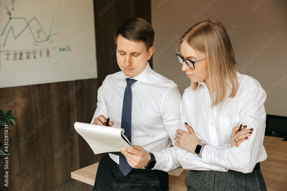 Two business people working with financial documents. Business colleagues are working in the office, discussing a business plan Two business people working with financial documents. Business colleagues are working in the office, discussing a business plan