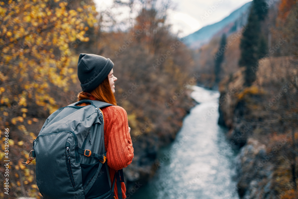 woman hiker with backpack on her back near mountain river in nature woman hiker with backpack on her back near mountain river in nature