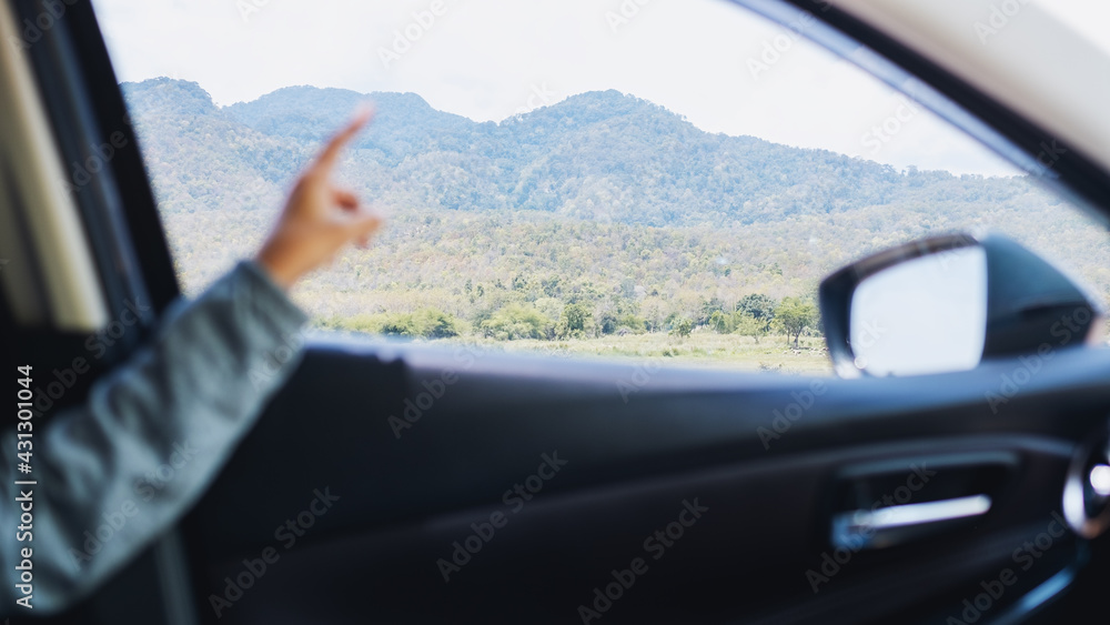 A young woman pointing finger at the mountains view while riding in a car A young woman pointing finger at the mountains view while riding in a car