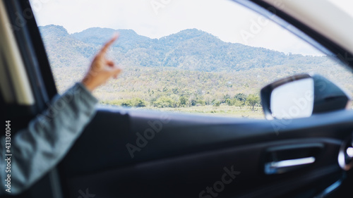 A young woman pointing finger at the mountains view while riding in a car