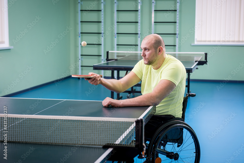 Adult disabled man in a wheelchair training before play at table tennis Adult disabled man in a wheelchair training before play at table tennis