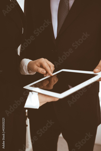 Businessman and woman using tablet computer for discussing questions in office. Partners or colleagues at meeting. Business cooperation concept
