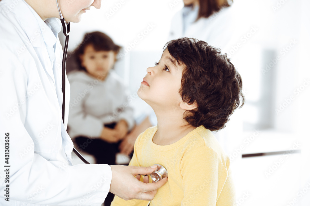 Woman-doctor examining a child patient by stethoscope. Cute arab boy at physician appointment. Medicine help concept Woman-doctor examining a child patient by stethoscope. Cute arab boy at physician appointment. Medicine help concept