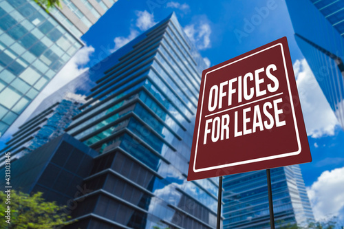An offices for lease sign in front of a modern glassy commercial Grade A building.