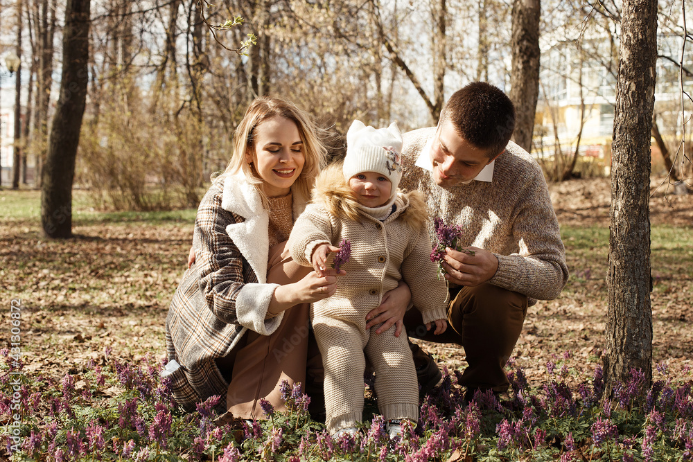 Fototapeta premium A young, beautiful couple is walking in the park with their little daughter.