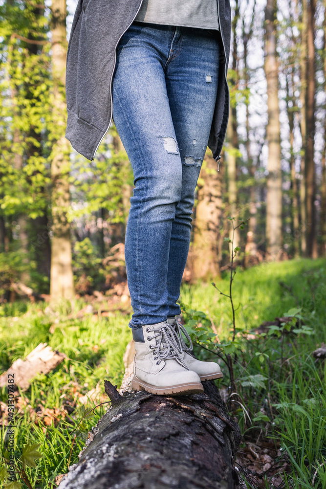 Hiking in forest. Woman wearing jeans and standing on tree trunk at woodland. Active lifestyle in nature Hiking in forest. Woman wearing jeans and standing on tree trunk at woodland. Active lifestyle in nature