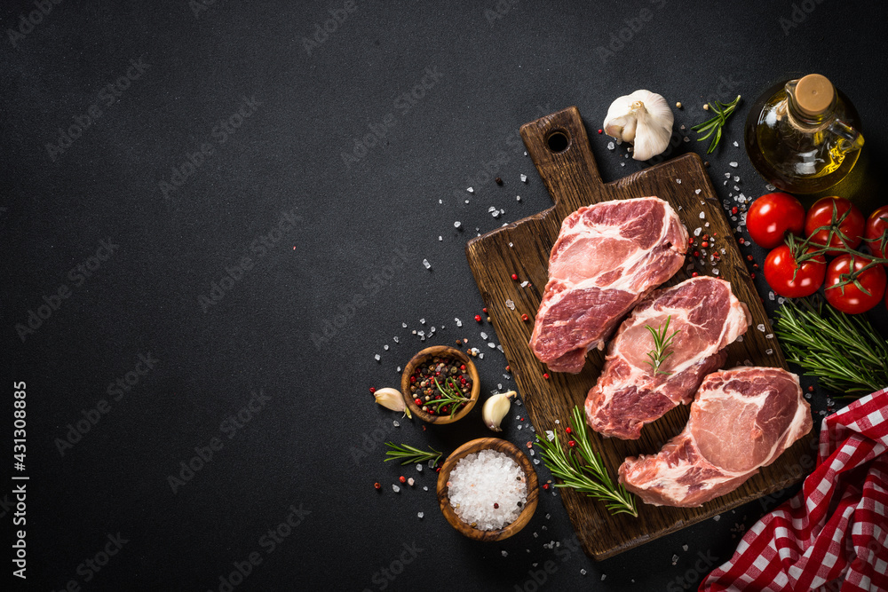 Pork meat at wooden board on black table.