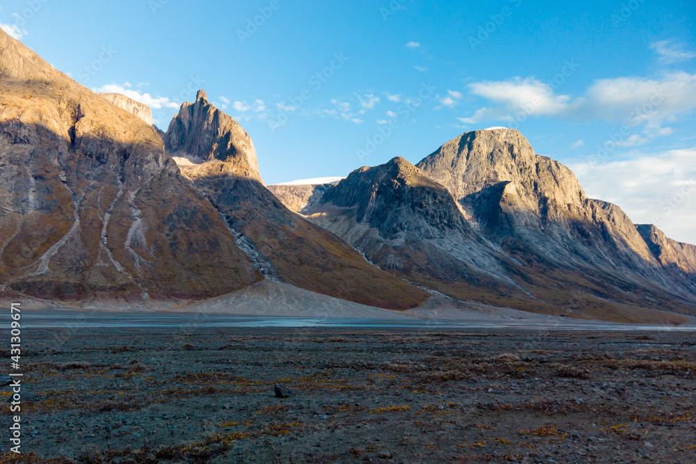 Sunset at the end of a sunny summer day in a remote arctic valley of Akshayuk Pass, Baffin Island, Canada. Last rays of sunlight light up surrounding peaks