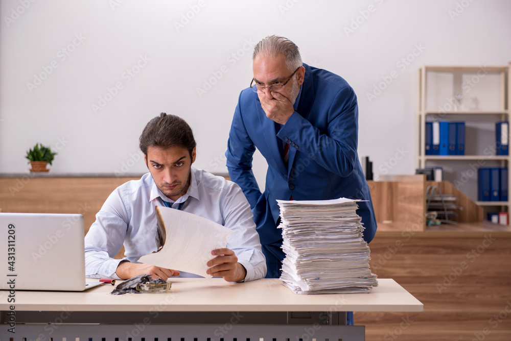 Young male employee and old boss burning papers at workplace Young male employee and old boss burning papers at workplace