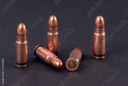 Fototapeta Five bronze pistol bullets on black board, closeup detail