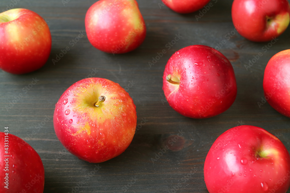 Closeup red fresh ripe apples with water droplets scattered on dark brown wooden table Closeup red fresh ripe apples with water droplets scattered on dark brown wooden table