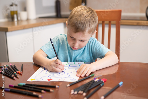 The child boy does tasks for the development of logical thinking, classes with a speech therapist at home, neuropsychology, autism, homework.