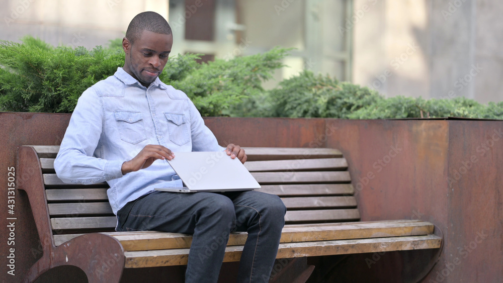 Obraz premium African Man Closing Laptop to Leave Bench 