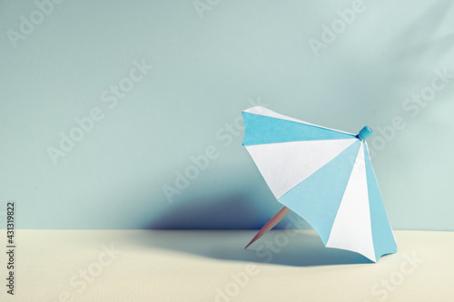 Beach umbrella with paper on blue background and shadow from palm tree © sergign