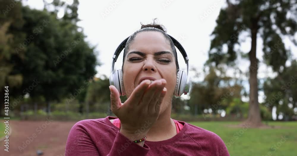Curvy woman sending kisses in camera while doing jogging routine outdoor at city park - Plus size and workout exercises Curvy woman sending kisses in camera while doing jogging routine outdoor at city park - Plus size and workout exercises