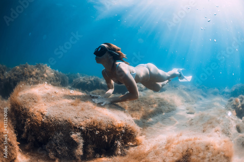 Freediver woman glides on deep sea. Free diver with fins posing underwater in ocean