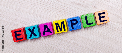 On a light wooden background on multi-colored bright wooden cubes the word EXAMPLE