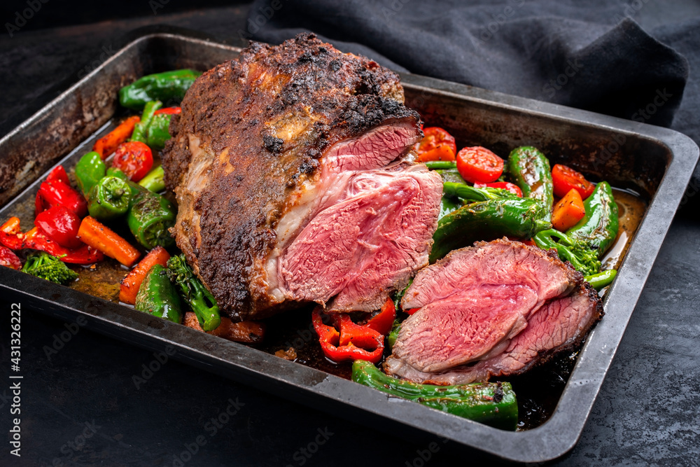 Traditional English barbecue lamb roast with vegetable and gravy sauce offered as close-up in a rustic metal tray