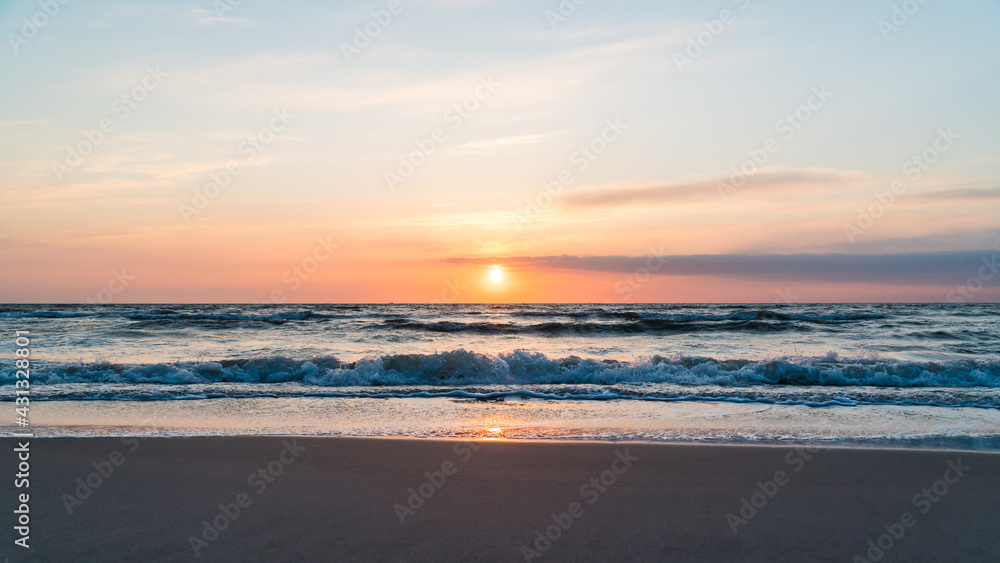 Wide shot of orange sunrise over the ocean at the beach on the German island Rügen at the baltic sea