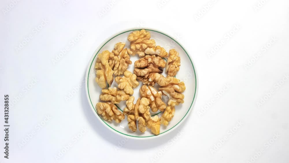 Stop motion animation. Walnut kernels move on a saucer. Top view.