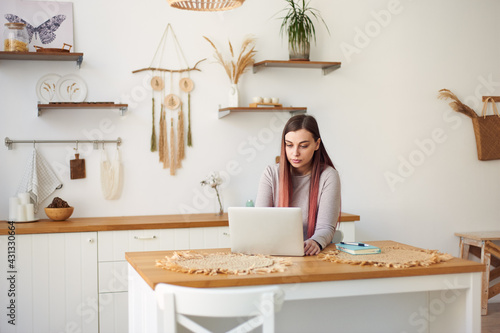 young woman with long hair works remotely on laptop at home, distant education. Freelance work. Teaching students online.