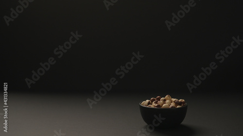 roasted hazelnuts in black bowl on black paper background