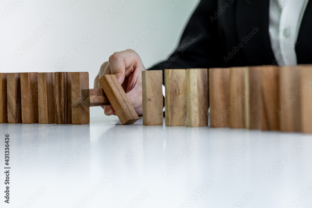 Close up finger businesswoman stopping wooden block from falling in the line of domino with Investment Insurance Alternative and preven,Business risk contro concept. Close up finger businesswoman stopping wooden block from falling in the line of domino with Investment Insurance Alternative and preven,Business risk contro concept.