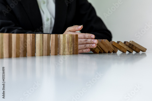 Close up finger businesswoman stopping wooden block from falling in the line of domino with Investment Insurance Alternative and preven,Business risk contro concept.