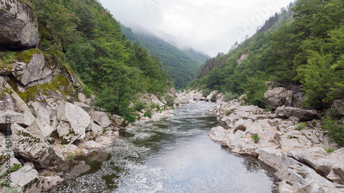 River stream on a green valley in an amazing and peaceful national park with fog and cloudy. Rural scenery mount and canyon in the balkan