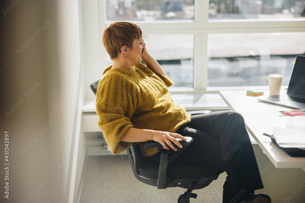 Female executive talking over phone sitting at her desk Female executive talking over phone sitting at her desk