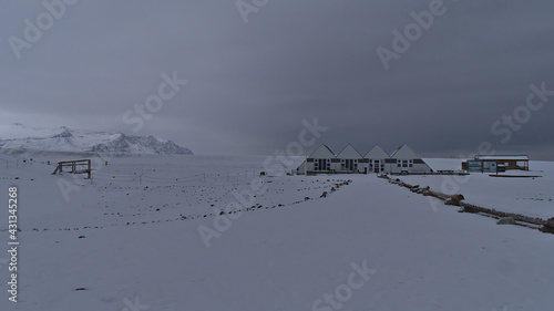 View of deserted parking and cafe at Jökulsárlón glacier lagoon, Vatnajökull national park, Iceland in winter (off-season) with snow-covered path and rugged mountains in background on cloudy day. © Timon