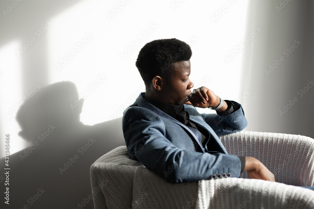 portrait of a young african man in a suit sitting in a chair 