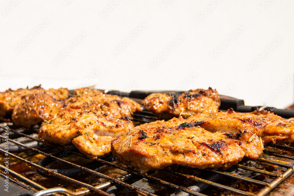 Close-up of pork steaks on a garden electric grill. Isolated on white background.