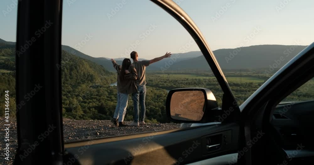 Young Traveler Couple on Road Trip, Man and Woman Enjoying Journey on Their Car Over Beautiful Landscape Young Traveler Couple on Road Trip, Man and Woman Enjoying Journey on Their Car Over Beautiful Landscape