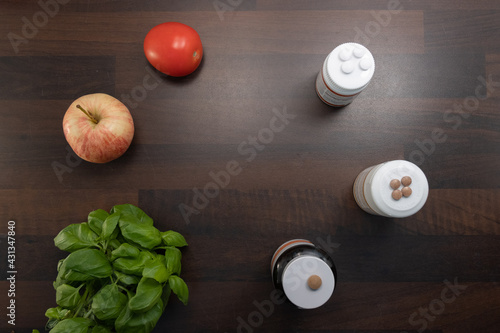 substitutes, apple, tomato and basil laying on a wooden table signalling ambitions for an improved lifestyle in the future