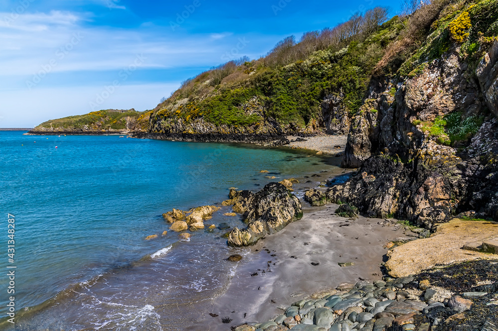 A view along the rocky shore beside the harbour entrance at Lower Fishguard, South Wales on a sunny day