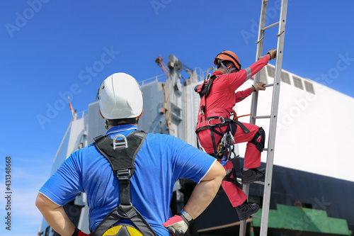 Team works Mechanic wearing seat belts, safety harness, going up stairs fixed, working at heights in industrial plants, preventing falls from heights, wearing protective equipment for safety concept.