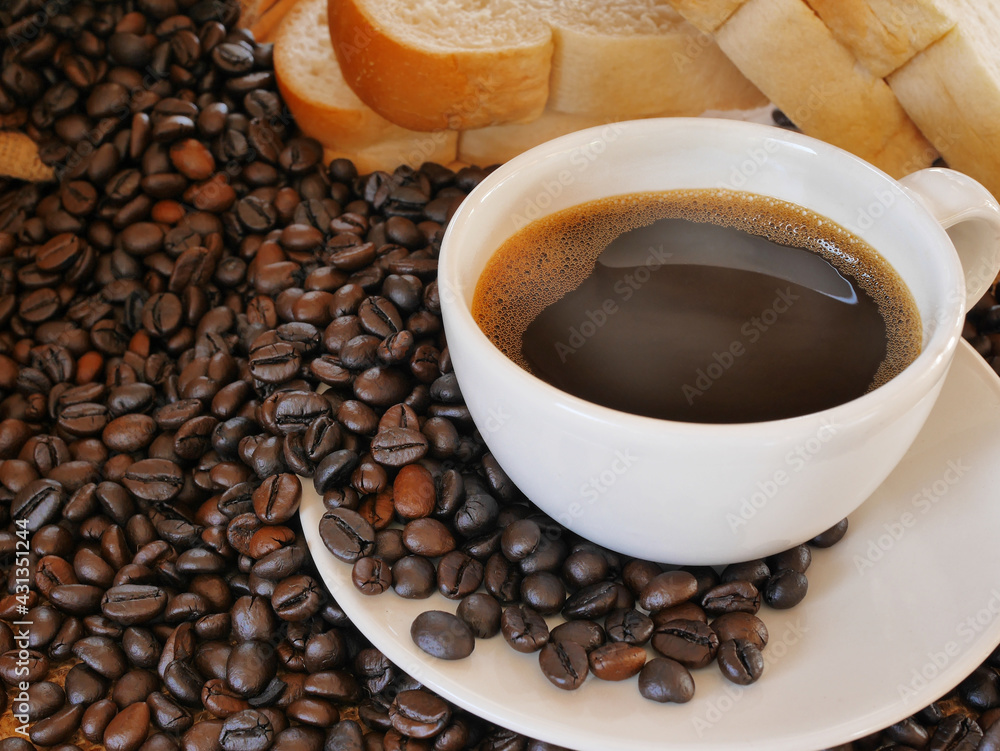 Fototapeta premium A cup of hot aroma coffee and a lot of coffee beans with some breads for this breakfast