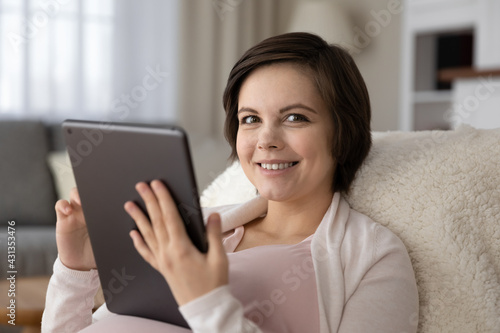 Close up portrait of smiling Caucasian pregnant woman relax at home talk on video virtual call on pad. Happy female enjoy pregnancy have fun browse wireless internet on tablet. Technology concept.