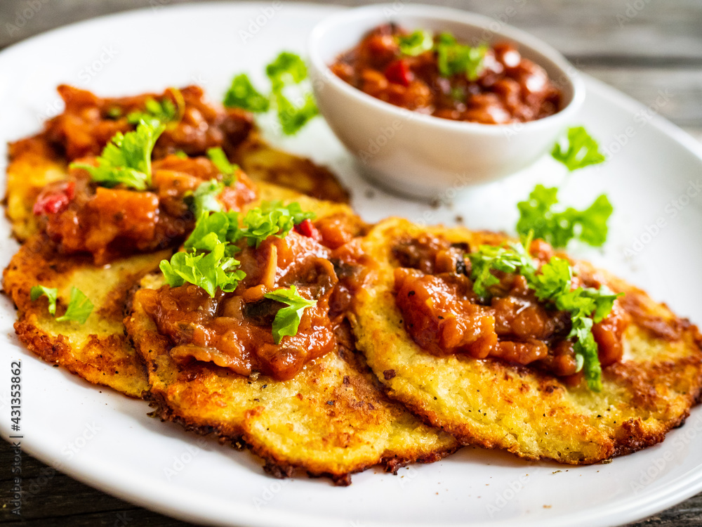 Potato pancakes with vegetable stew on wooden table Potato pancakes with vegetable stew on wooden table