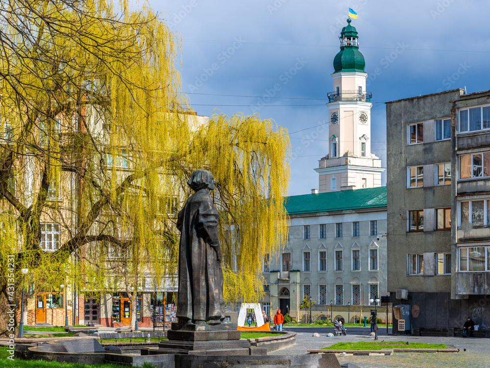 DROHOBYCH, UKRAINE - April 25, 2021: Monument to a Ukrainian philosopher Yuriy Drohobych and the Tower of Drohobych Town Hall. DROHOBYCH, UKRAINE - April 25, 2021: Monument to a Ukrainian philosopher Yuriy Drohobych and the Tower of Drohobych Town Hall.
