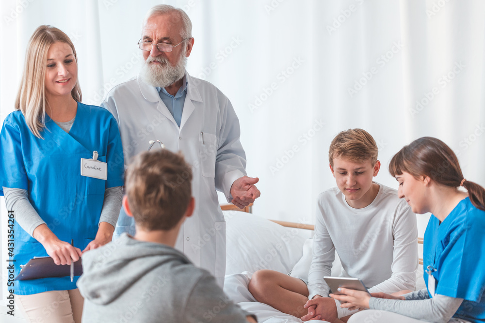 Obraz premium Senior male doctor with patient and female intern at the hospital