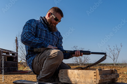Shooter loading shotgun at shooting range, soft focus, slight creative noise in photo