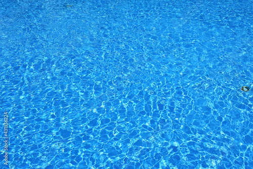 Rippled blue water surface. Water level in the pool. Light reflections on the surface of the water full of ripples.