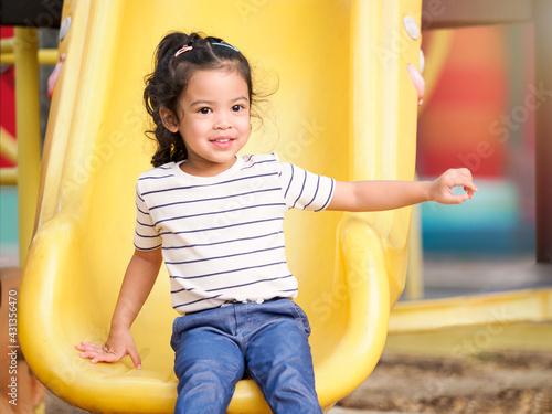 A cute Asian girl resting after having fun playing the slider in the playground