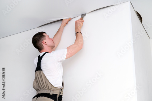 Φωτογραφία worker installs a stretch ceiling. Construction